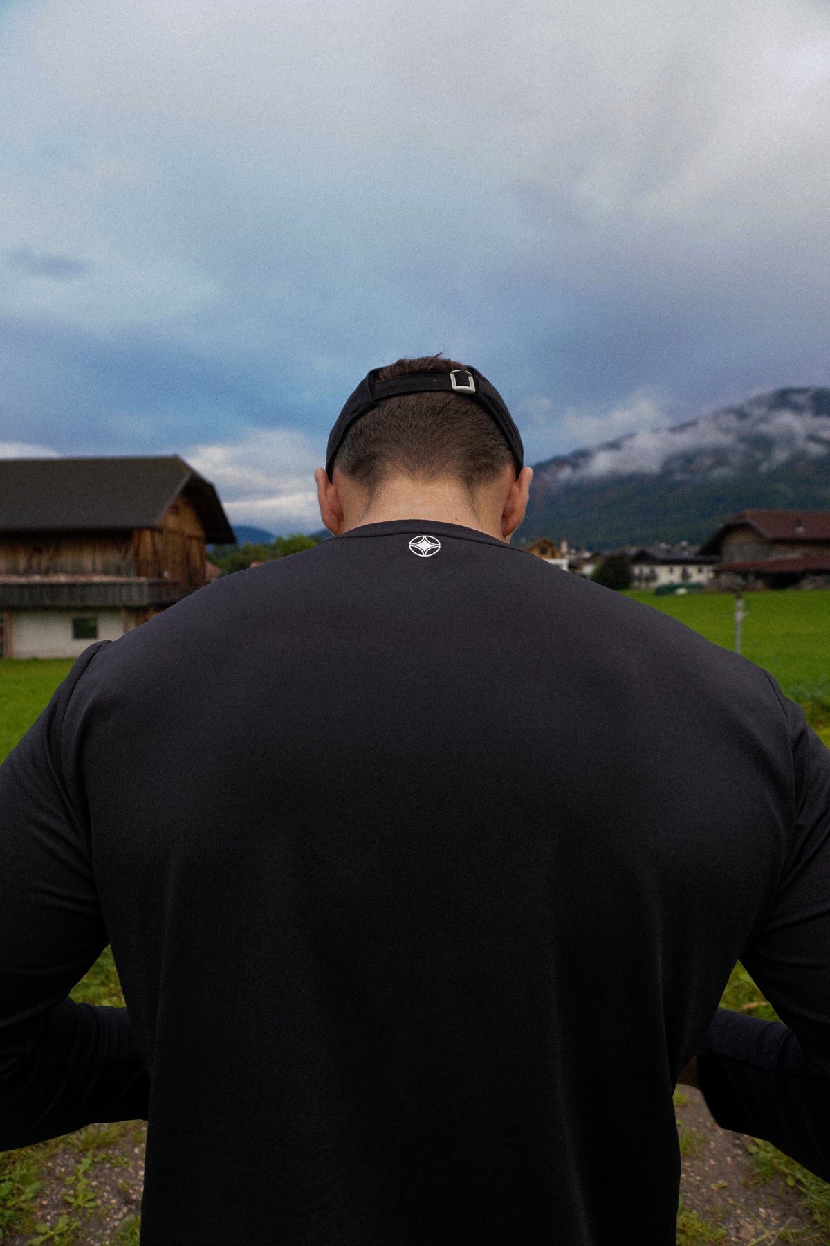 Model wearing the black seamless long sleeve tee, back view, in the mountains